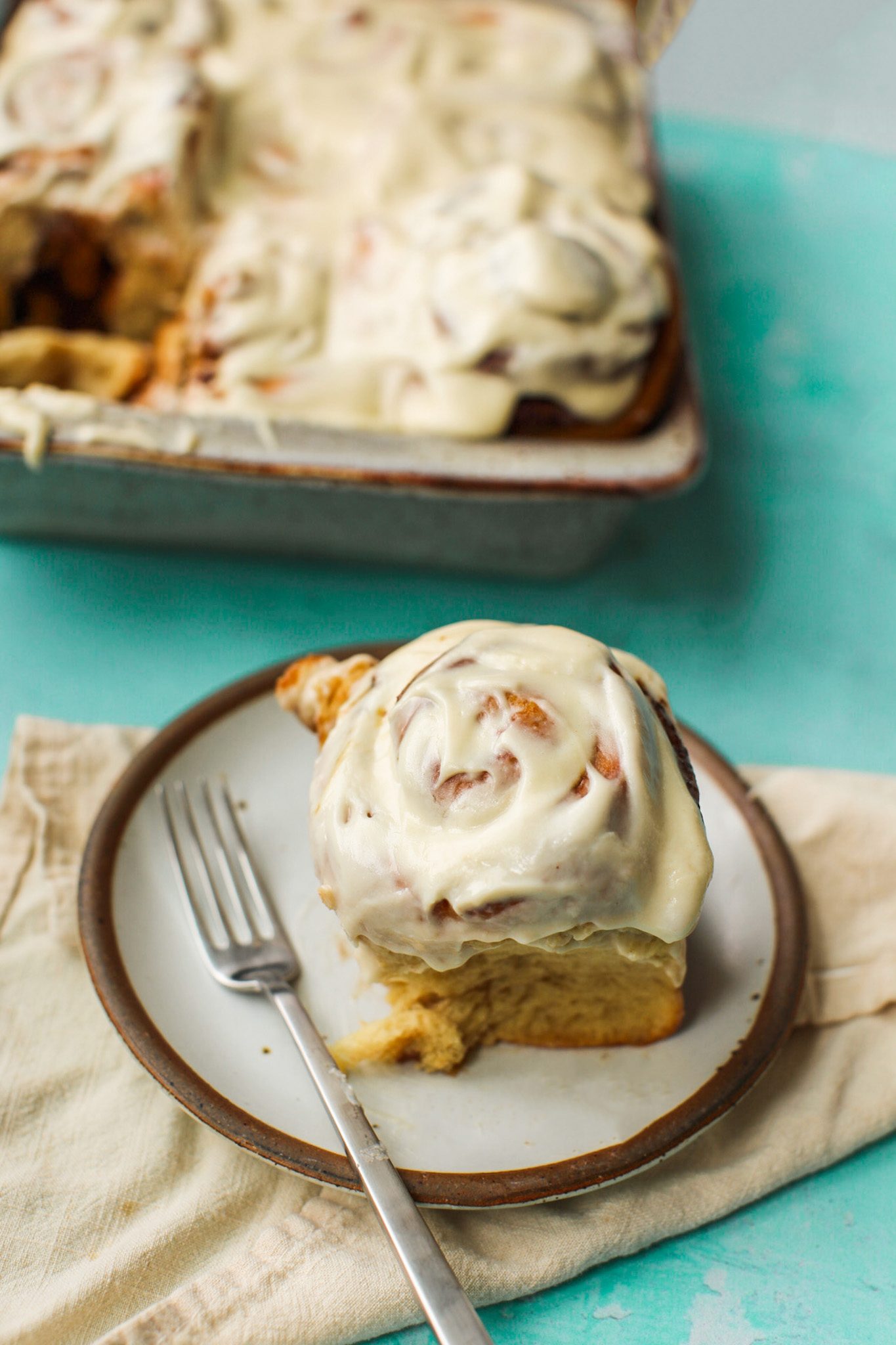 A frosted vegan cinnamon roll on a plate